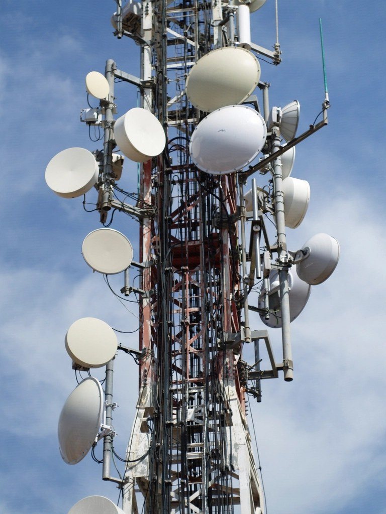 Cell tower antennas and microwave dishes against the sky