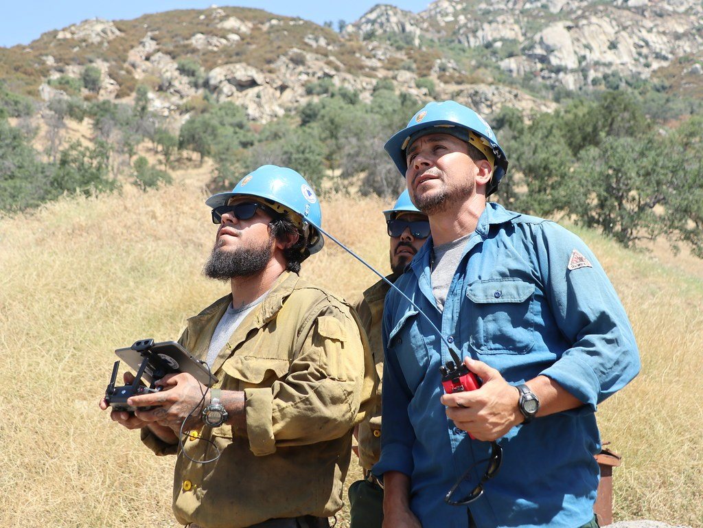 Two drone pilots flying with controllers in open terrain